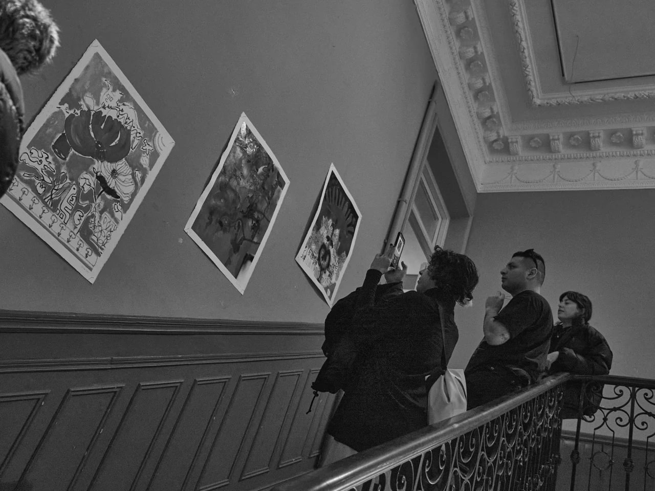 Visitantes observando obra gráfica en la escalera de El Imparcial