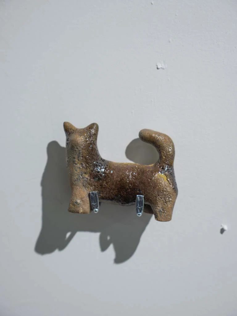 Escultura cerámica tubular con dos aberturas sobre pared