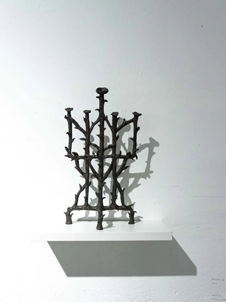 Escultura metálica vertical semejante a una trama vegetal