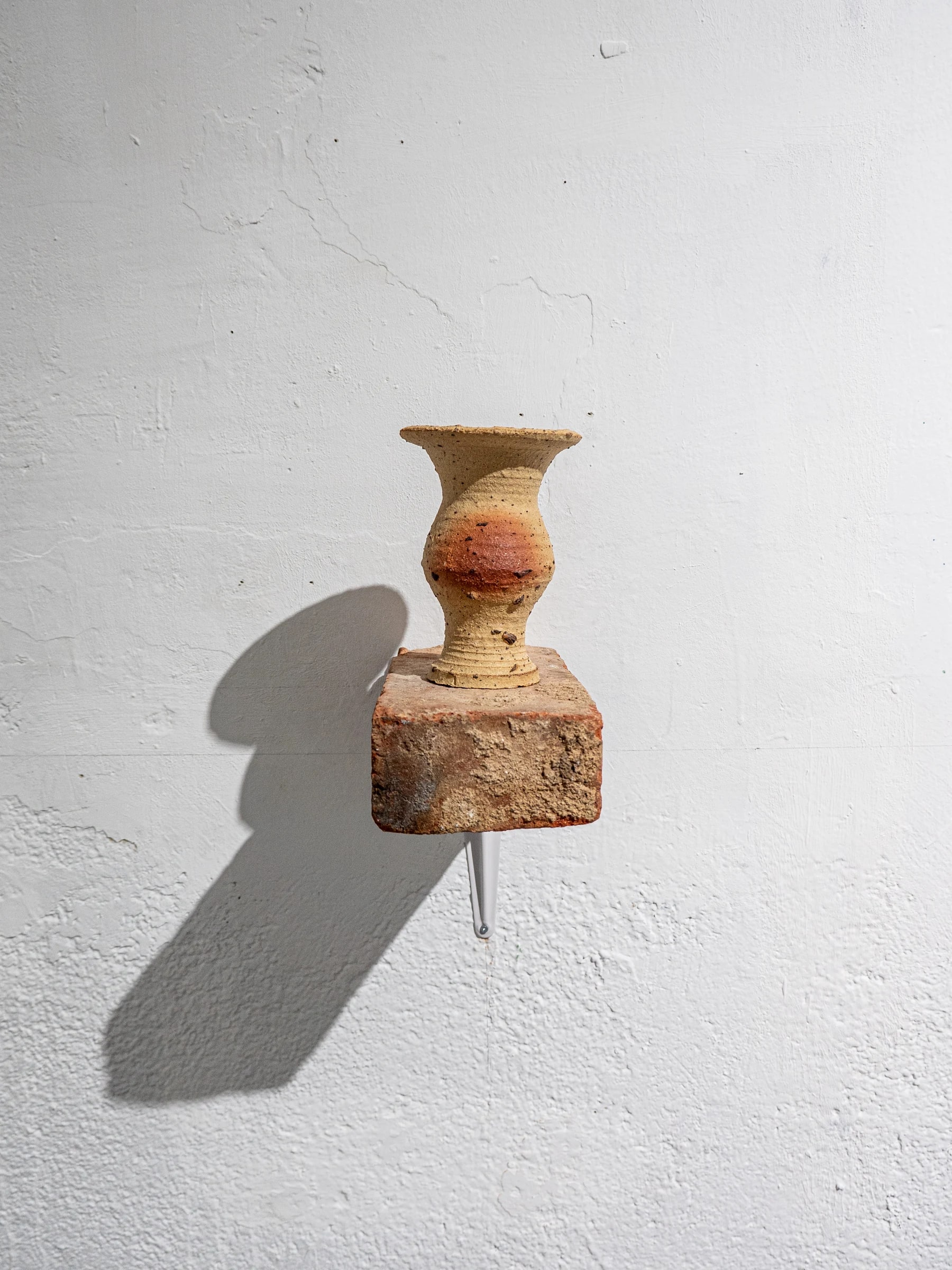 Vasija y fragmento cerámico instalados sobre una peana mineral