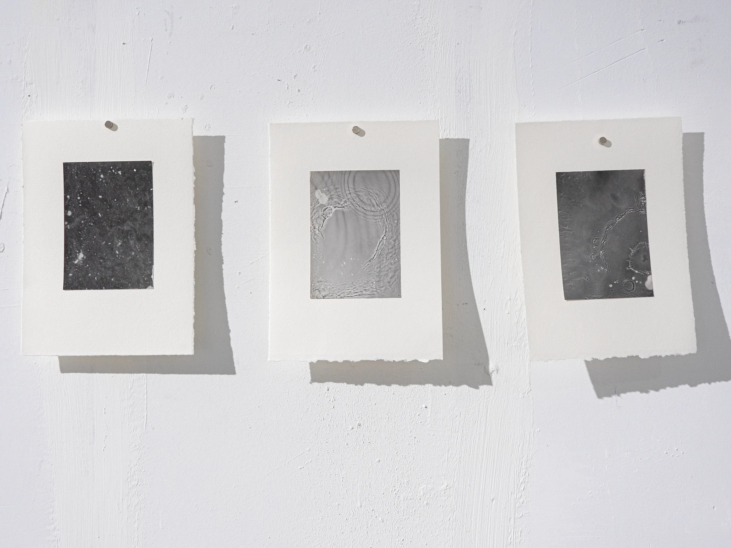 Serie de tres rayogramas oscuros montados sobre papel