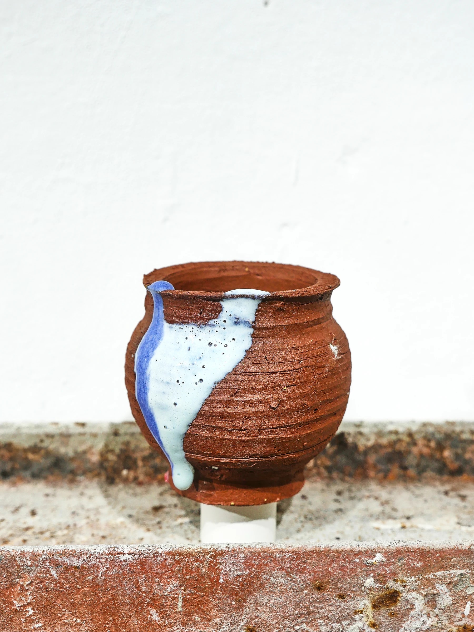 Vasija de arcilla local atravesada por un fragmento azul
