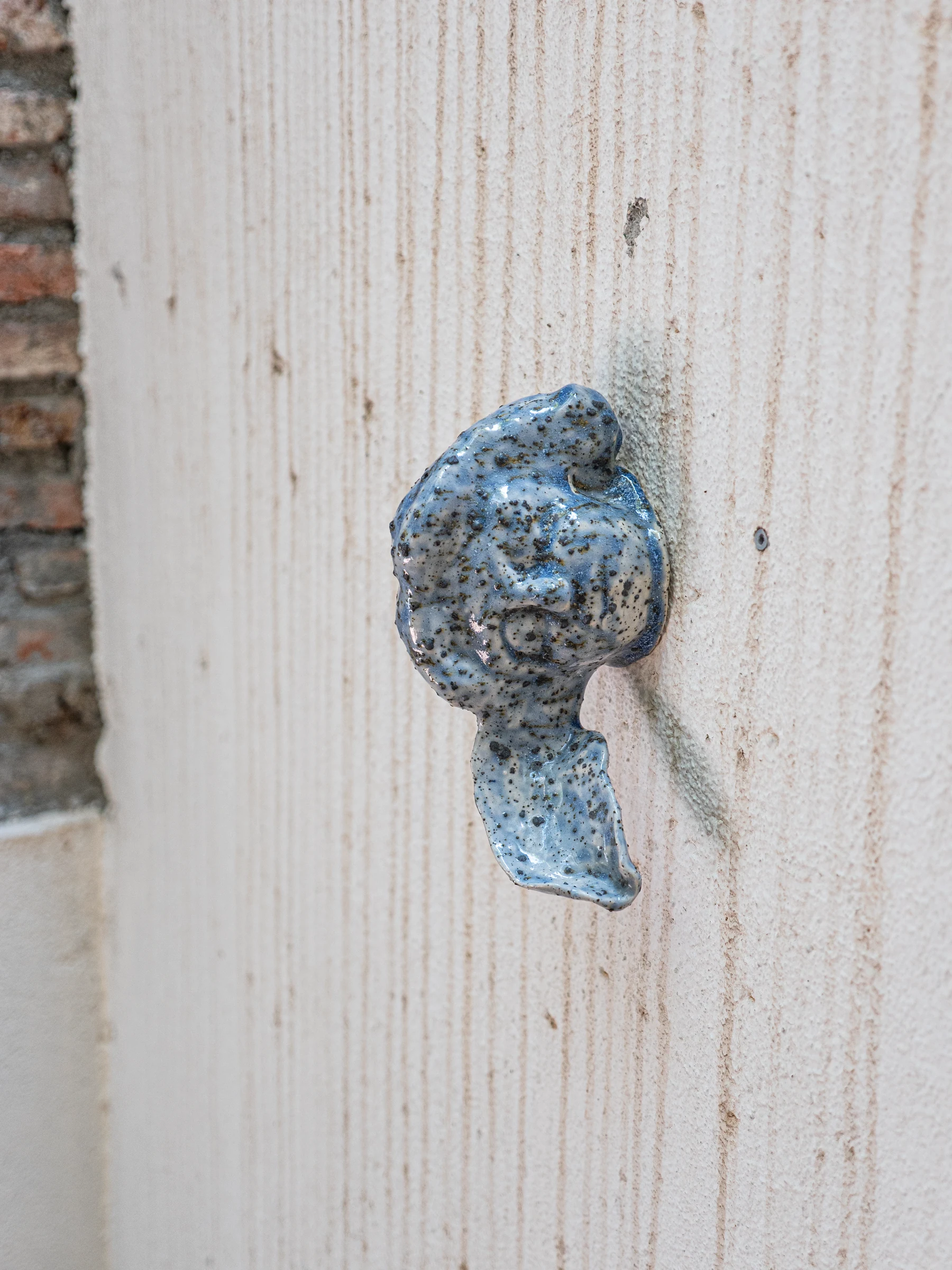 Pequeña pieza cerámica azul fijada a una puerta de madera