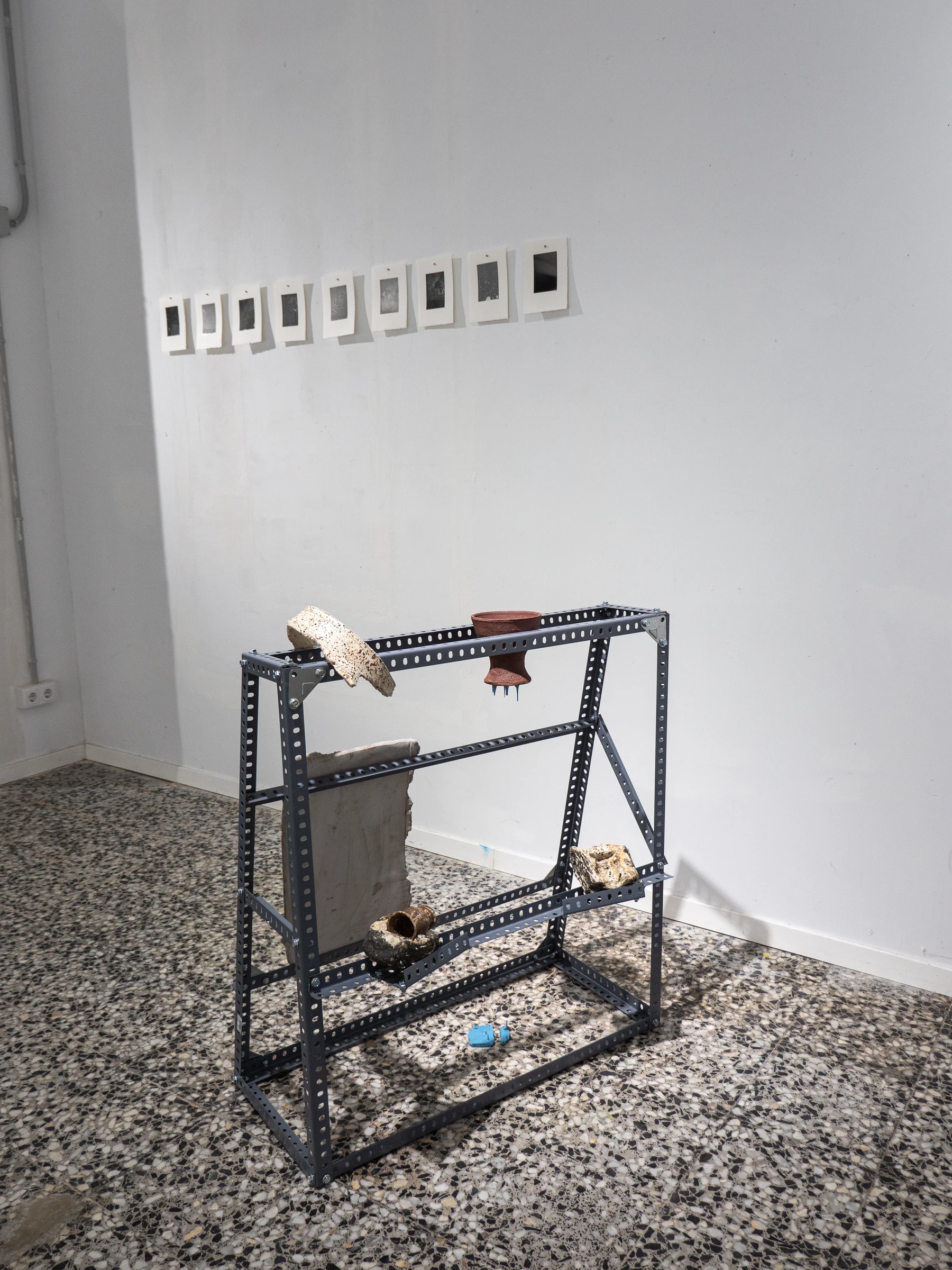 Carrito metálico con piezas frente a una serie de fotografías