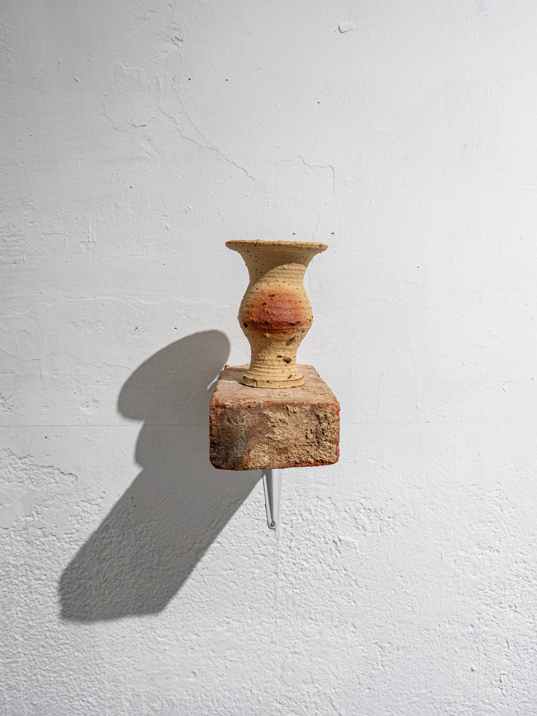 Vasija y fragmento cerámico instalados sobre una peana mineral