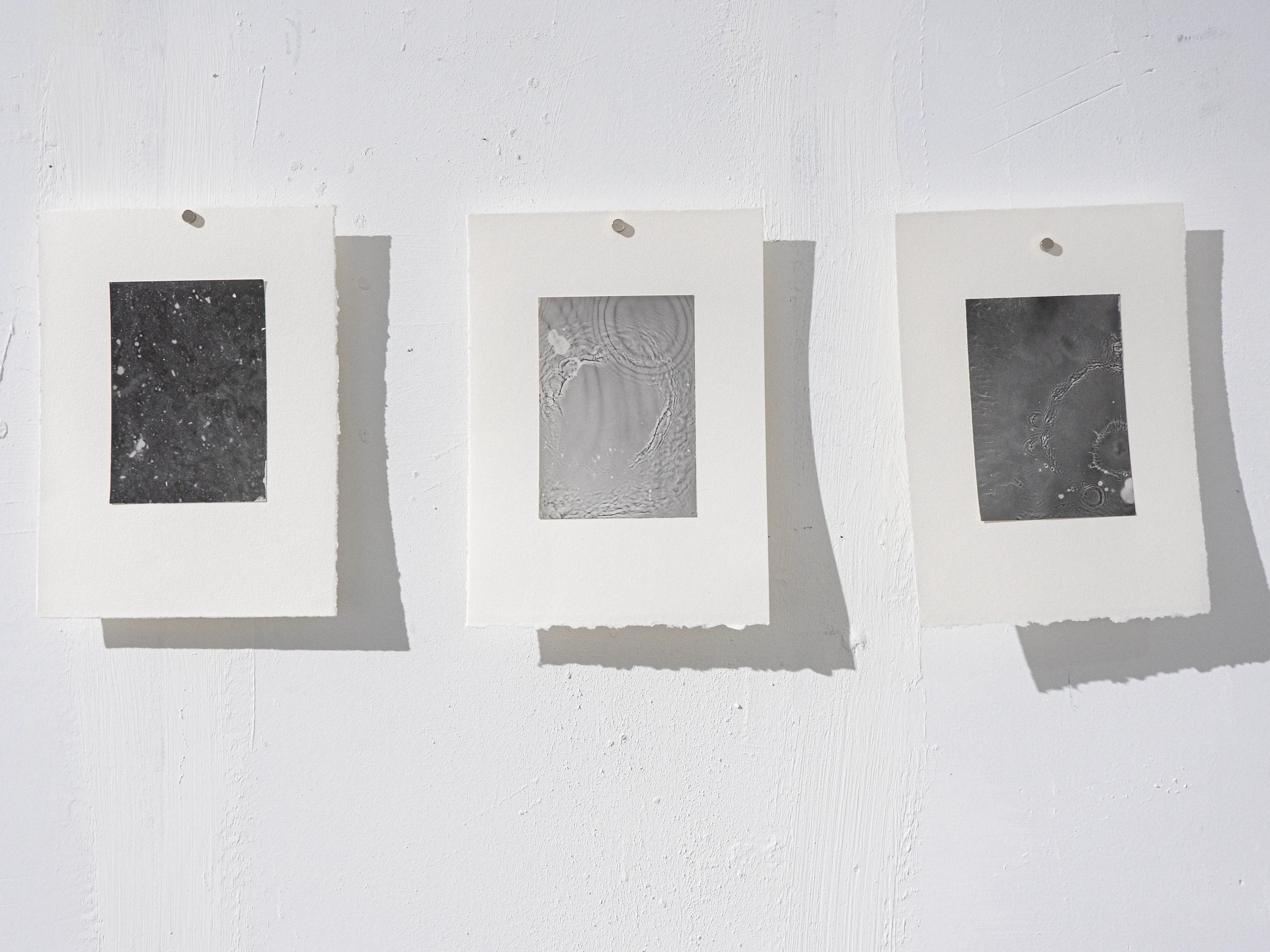 Serie de tres rayogramas oscuros montados sobre papel