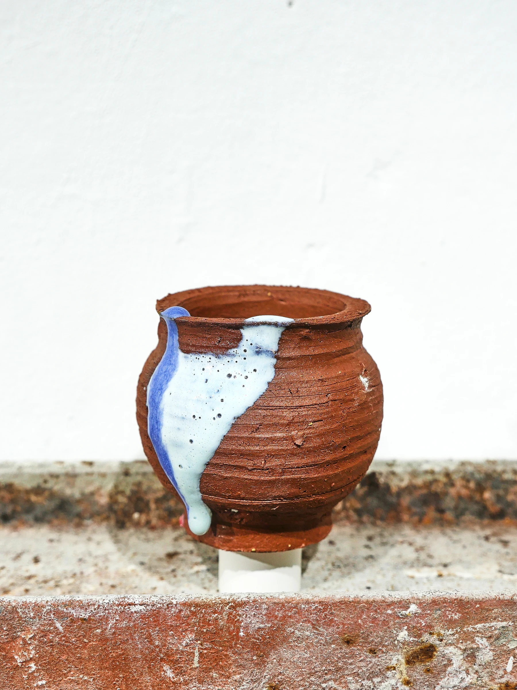 Vasija de arcilla local atravesada por un fragmento azul