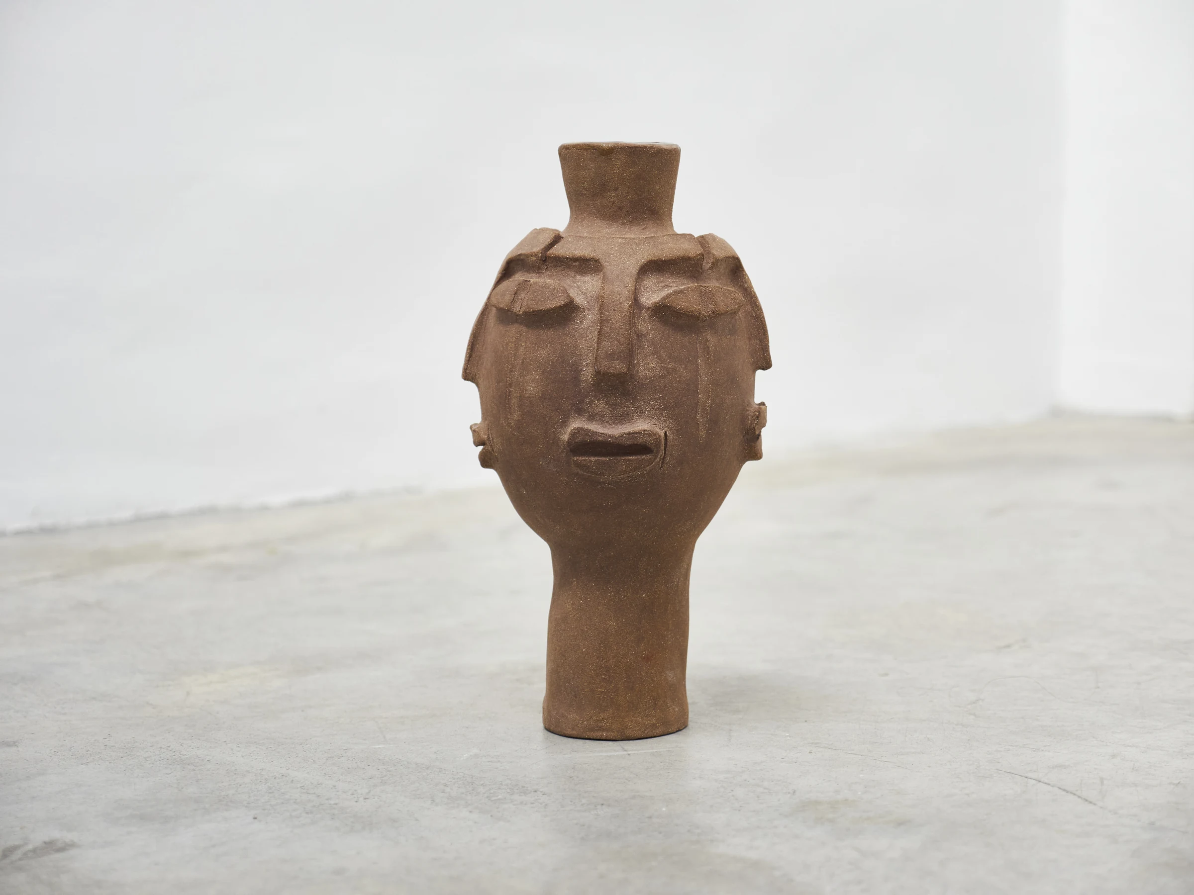 Escultura cerámica antropomorfa sobre fondo blanco